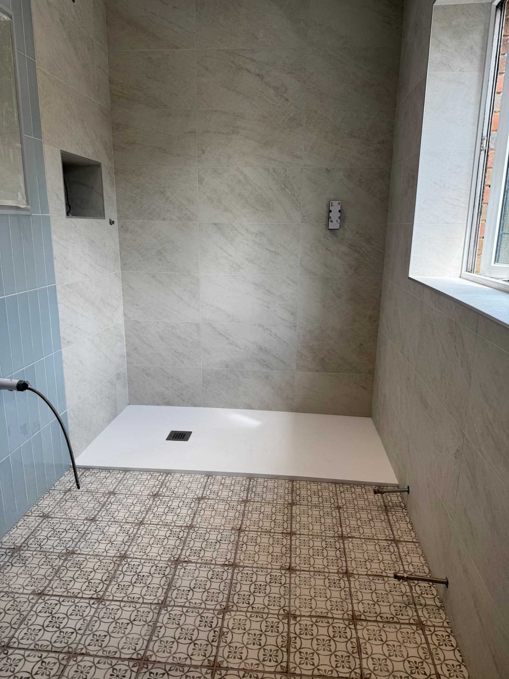 We've finished tiling this bathroom with large-format porcelain tiles on the walls and decorative patterned tiles across the floor to give it a really stylish look. The neutral tones and Victorian floor pattern create a clean finish that'll look great for years to come.