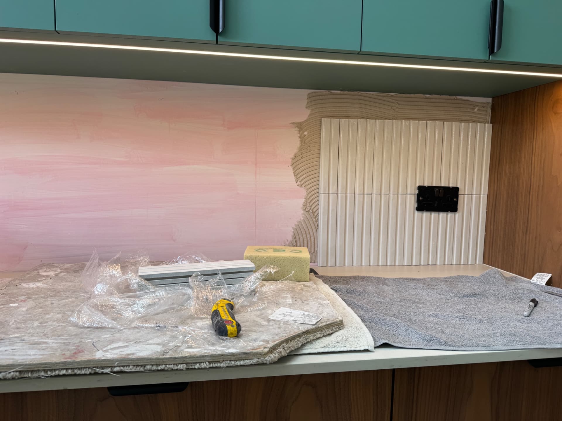 We've started tiling this splashback and planned the layout so the cuts around the existing socket fall at a sensible point on the tiles. Working around outlets takes a bit of time and precision, but getting the positioning right from the start makes the job run smoothly.